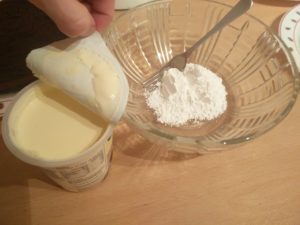 Sugar in a mixing bowl with a carton of cream open next to it