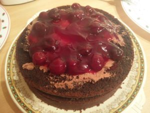 The cherries have been spread over the third layer of the cake