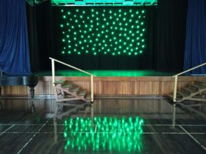 The star curtain lit up, with a reflection in the polished hall floor