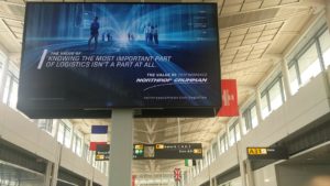A screen in the terminal building advertising Northrop Grumman's services